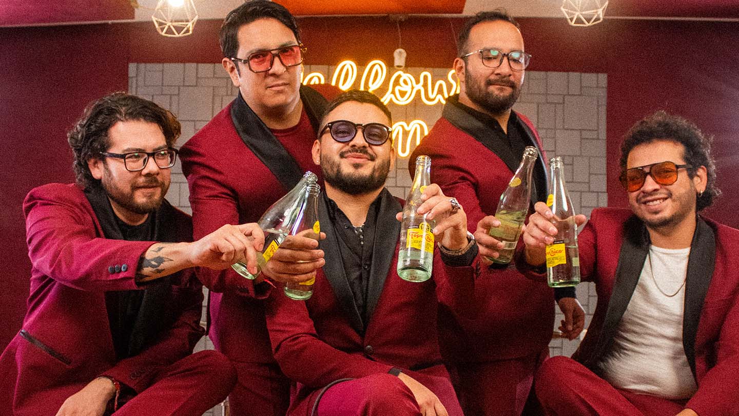 La Tigresa banda sosteniendo botellas de Topo Chico