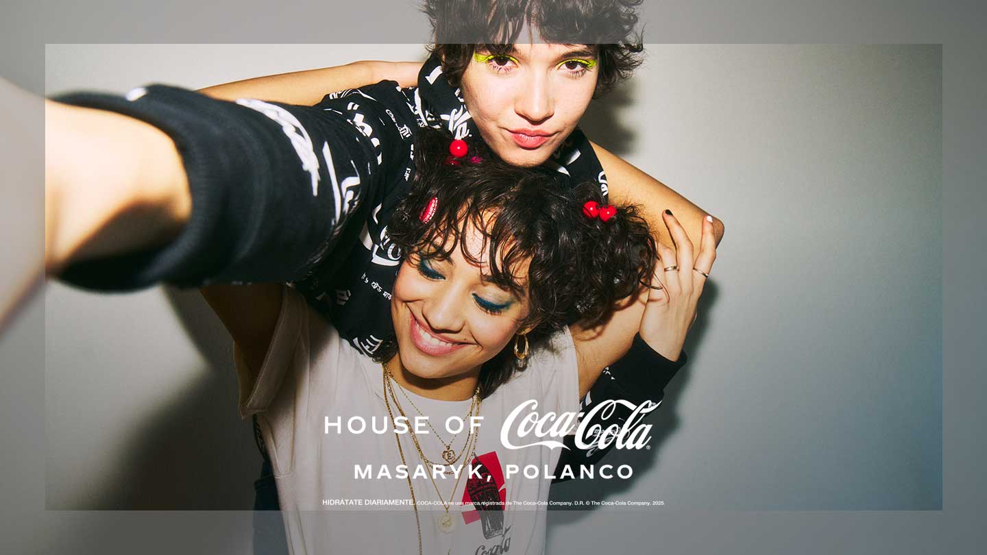 Dos personas jóvenes posan sonrientes durante una experiencia en House of Coca-Cola Masaryk, Polanco, en un ambiente casual y creativo.​