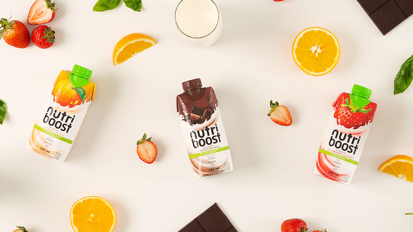 Top view of Nutriboost bottles in a white background with fruits and chocolates