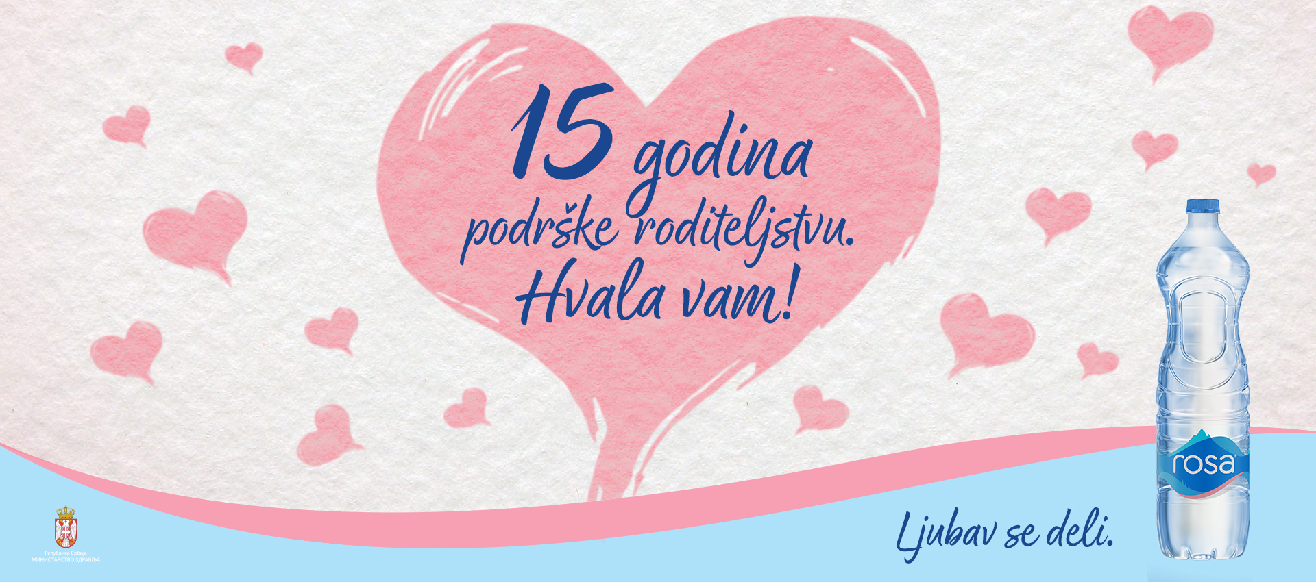 Alt tekst: Veliko ružičasto srce sa porukom o 15 godina i flaša vode „Rosa“ na desnoj strani.