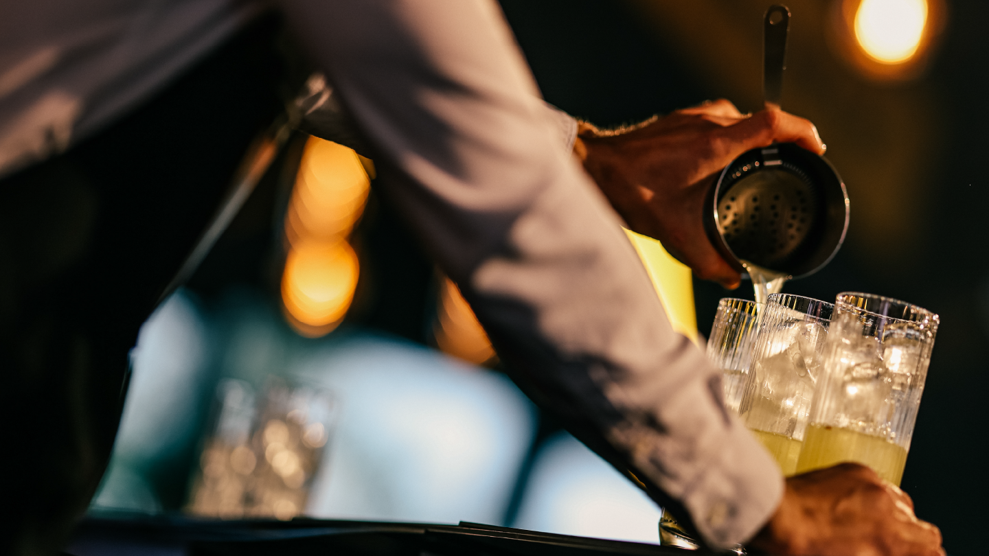 Barmen sipa žuti koktel sa ledom u visoke čaše uz promotivni tekst o takmičenju Schweppes Mixology Session 2025