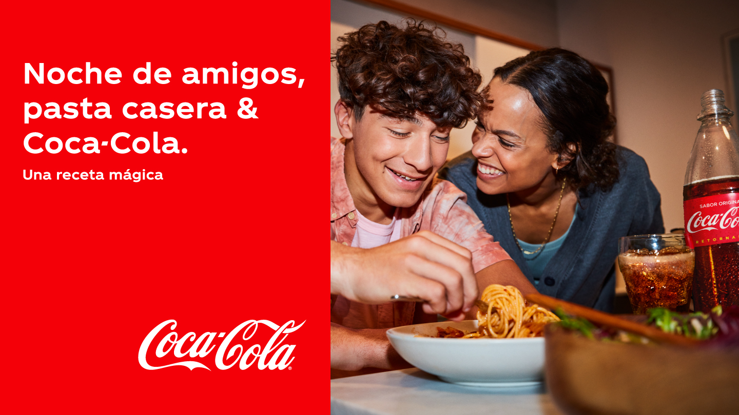 Dos amigos riendo mientras cenan spaghettis acompañado con una Coca-Cola. Texto: Noche de amigos, pasta casera & Coca-Cola. Una receta mágica.