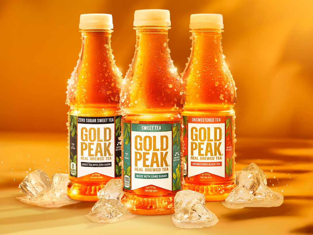 Three bottles of Gold Peak beverages with water splashing in around bottles