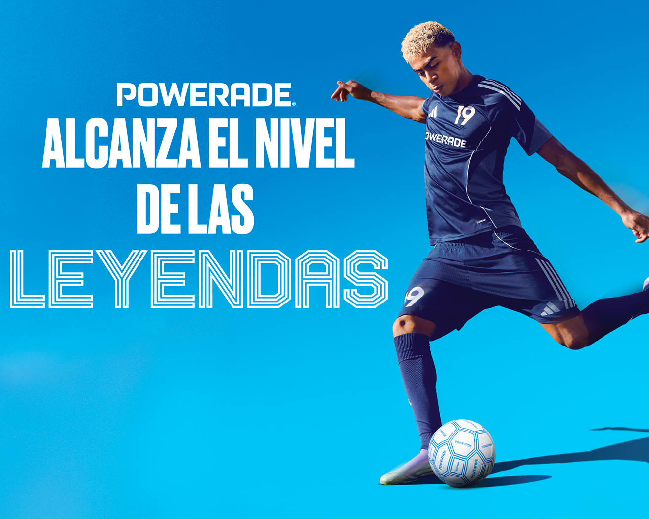 Jugador de futbol en uniforme azul Powerade patea balón bajo cielo azul junto al lema “Alcanza el nivel de las leyendas”.